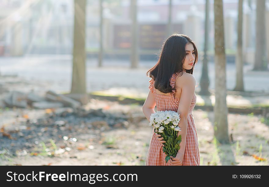 Woman Wearing Orange Sleeveless Dress Holding a Bouquet of Flowers
