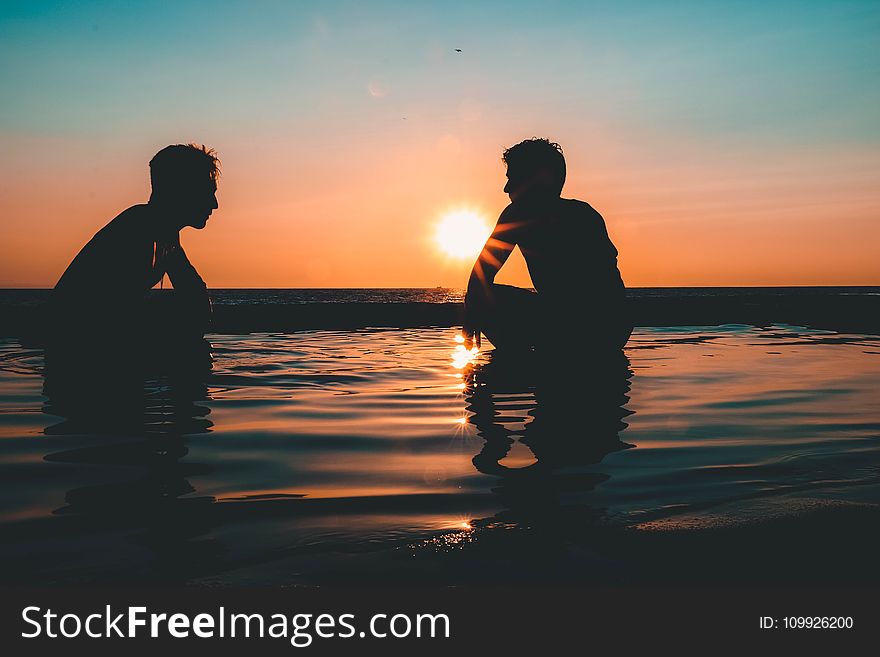 Photo of Two Men on Seashore during Sunset