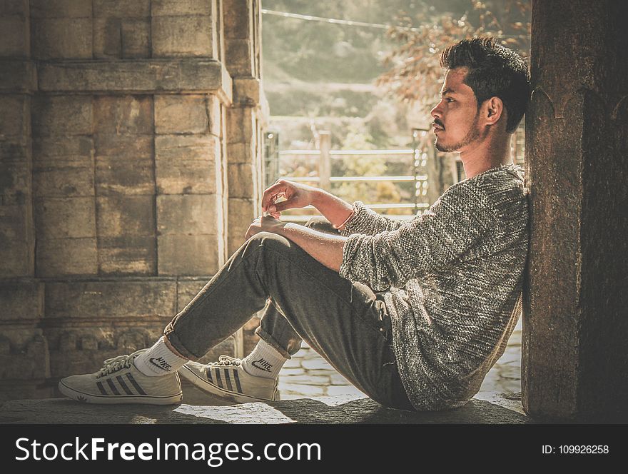 Photo Of Man Wearing Gray Sweater And Track Pants Leaning On Wall