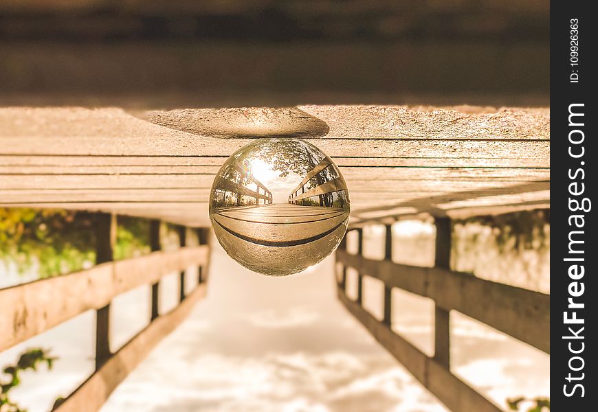 Macro Photography of Round Glass Ball on Top of Brown Wooden Dock