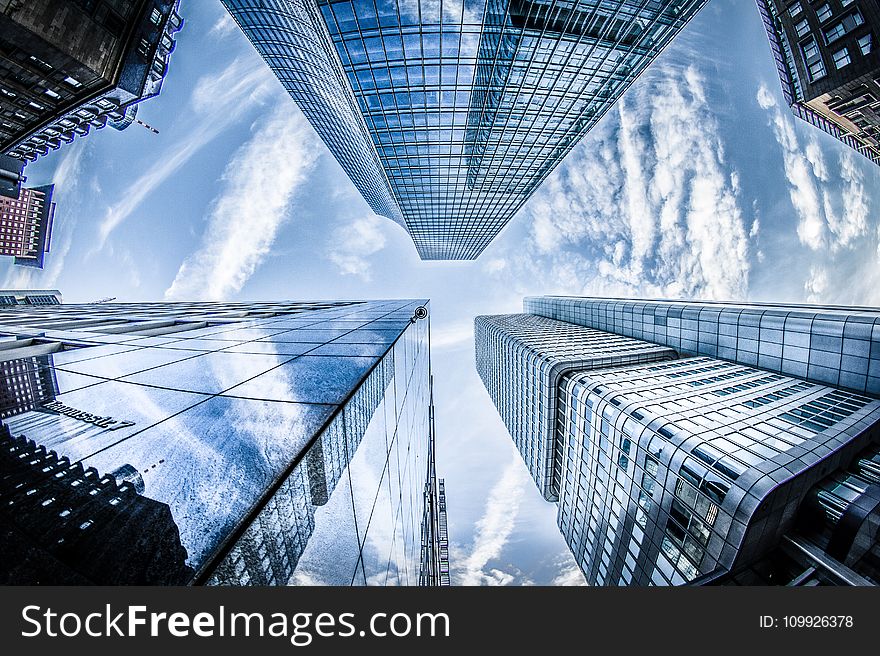 Low-angle Photo of Four High-rise Curtain Wall Buildings Under White Clouds and Blue Sky