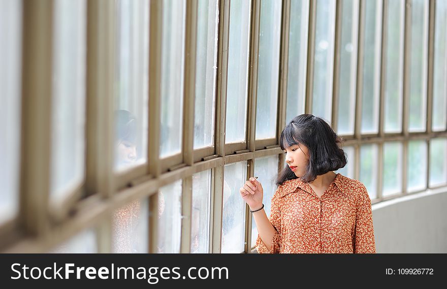 Woman Wearing Brown Dress Shirt While Sigh Seeing in Window