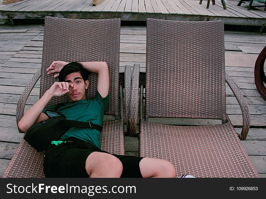 Man Wearing Green Shirt And Black Shorts Laying On Lounger