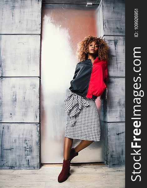 Woman in Red and Black Jacket Standing in Front of Brown Door