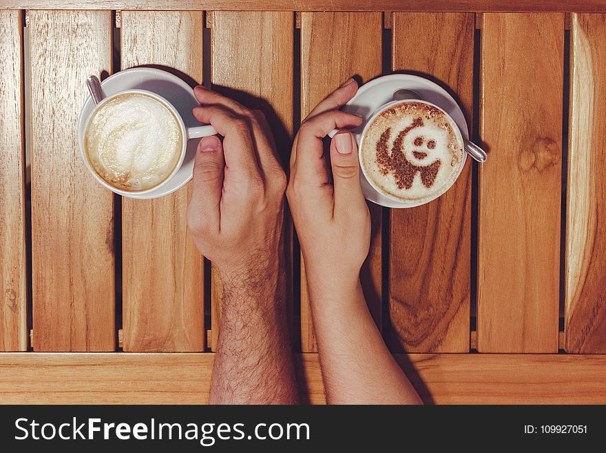 Person Holding Cup of Coffees on Table