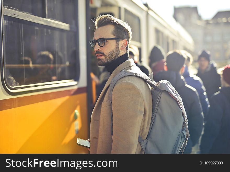 Man in Brown Coat and Gray Backpack Posing for a Photo