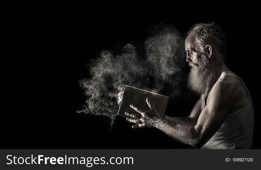 Man In White Tank Top Holding Book