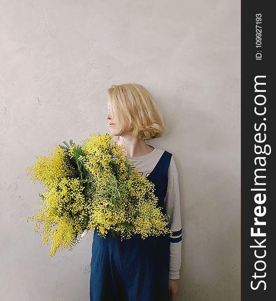 Woman Wearing Blue V-neck Sleeveless Top While Holding Yellow Petaled Flower