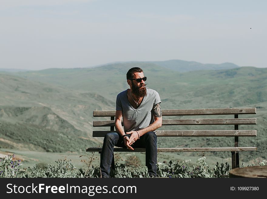 Photography of a Man Sitting on Wooden Bench