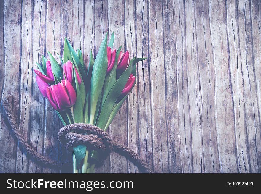 Red Tulip Bouquet On Top Of Brown Wooden Surface