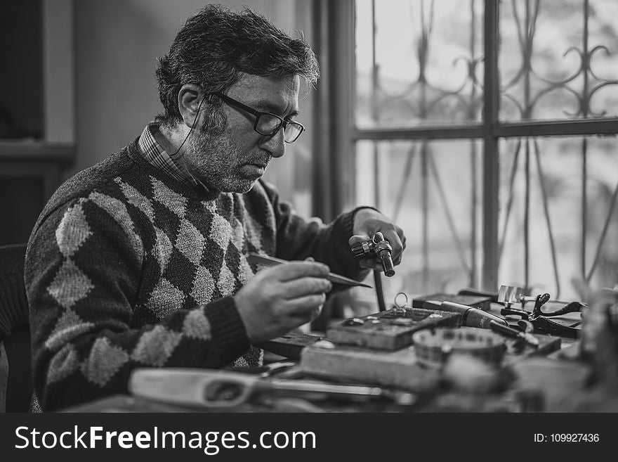 Grayscale Photo of Man Holding Tools