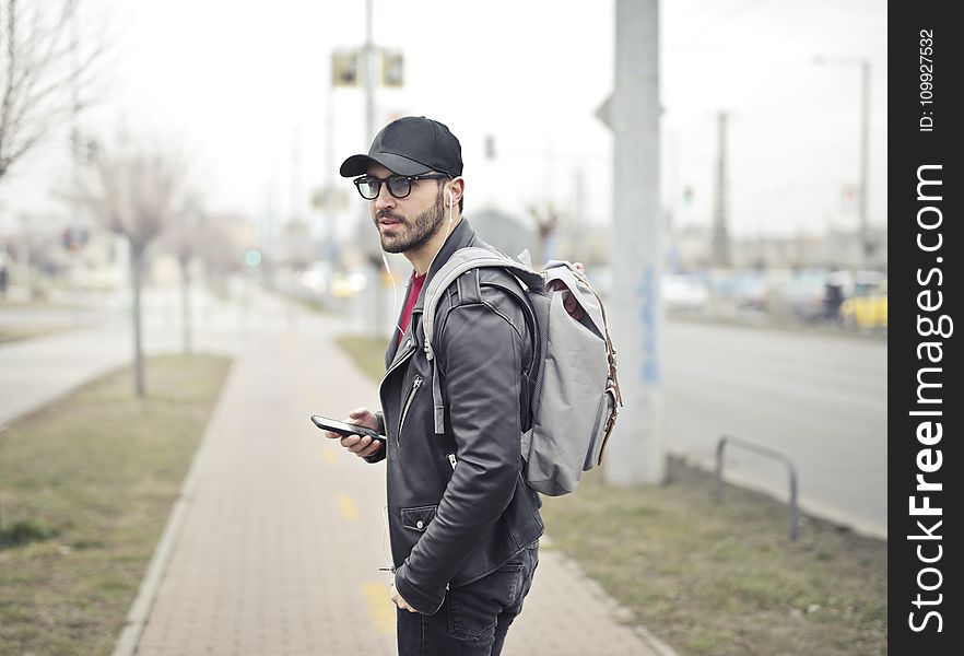 Man Wearing Black Leather Jacket Holding Smartphone