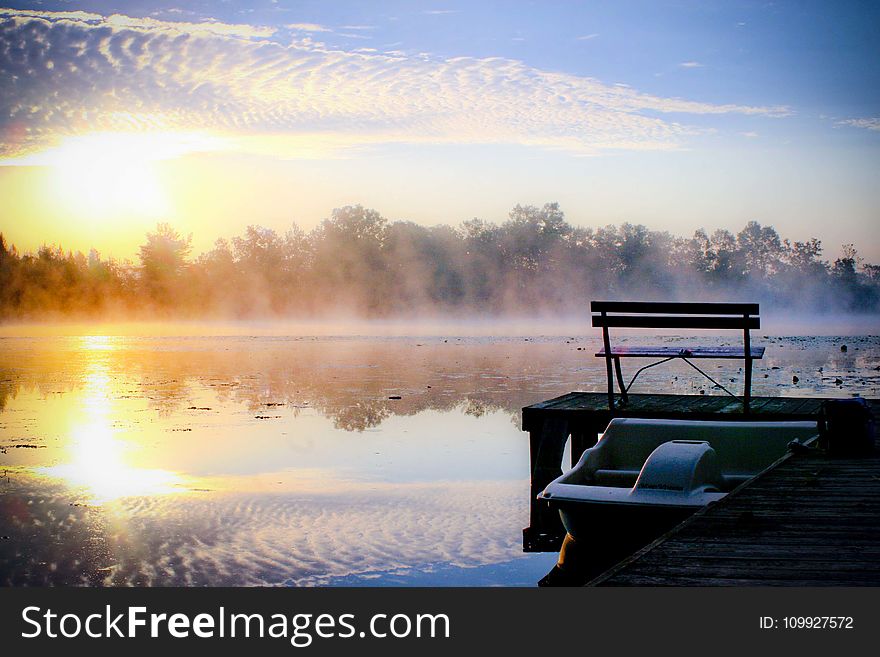 White Plastic Boat On Lake Beside Wooden Dock During Golden Hour