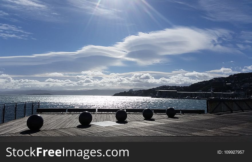 Five Balls Placed On Gray Wooden Platform Near Sea