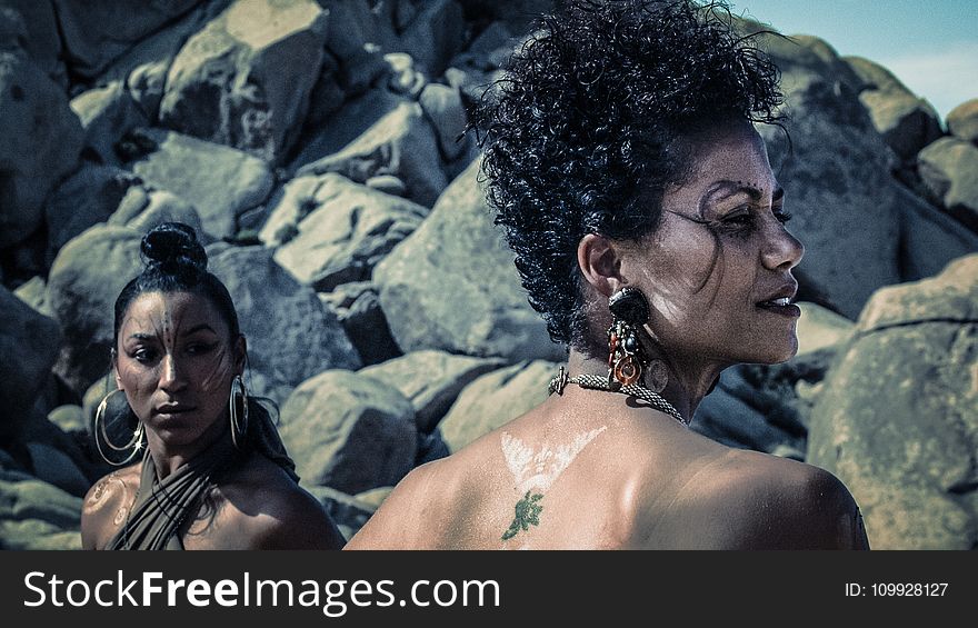 Photo of Two Women With Tattoos Standing Near Rocks
