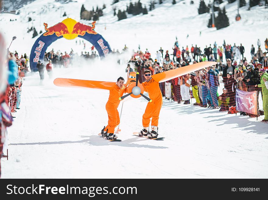 Photography of Men in Orange Suits Ridding Snowboard