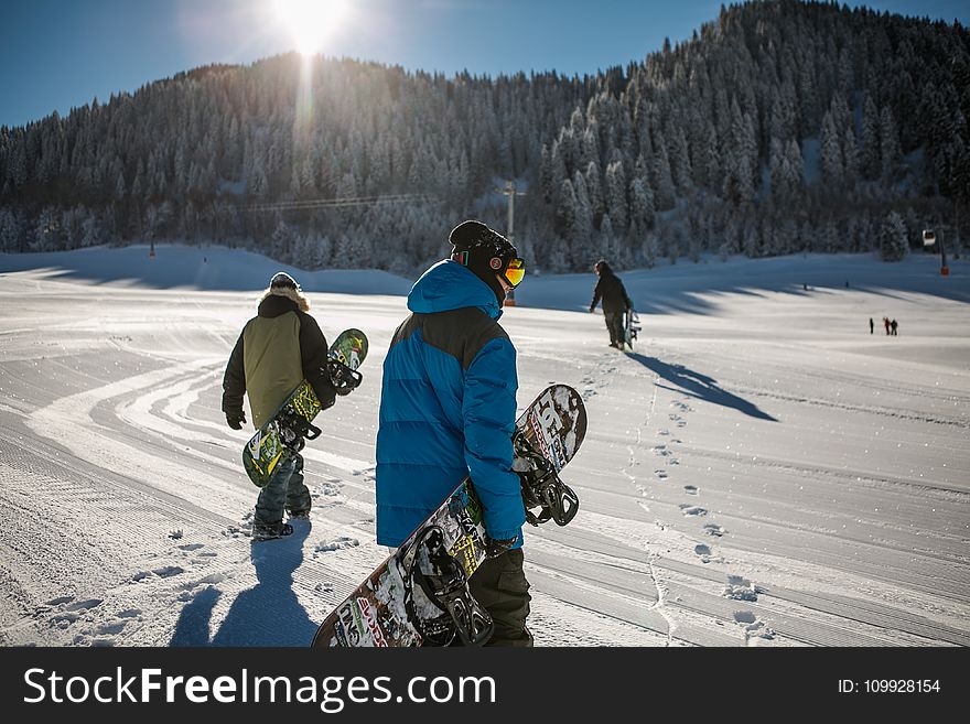 Person Wearing Blue Winter Jacket Carrying Snowboard Under Sunny Sky