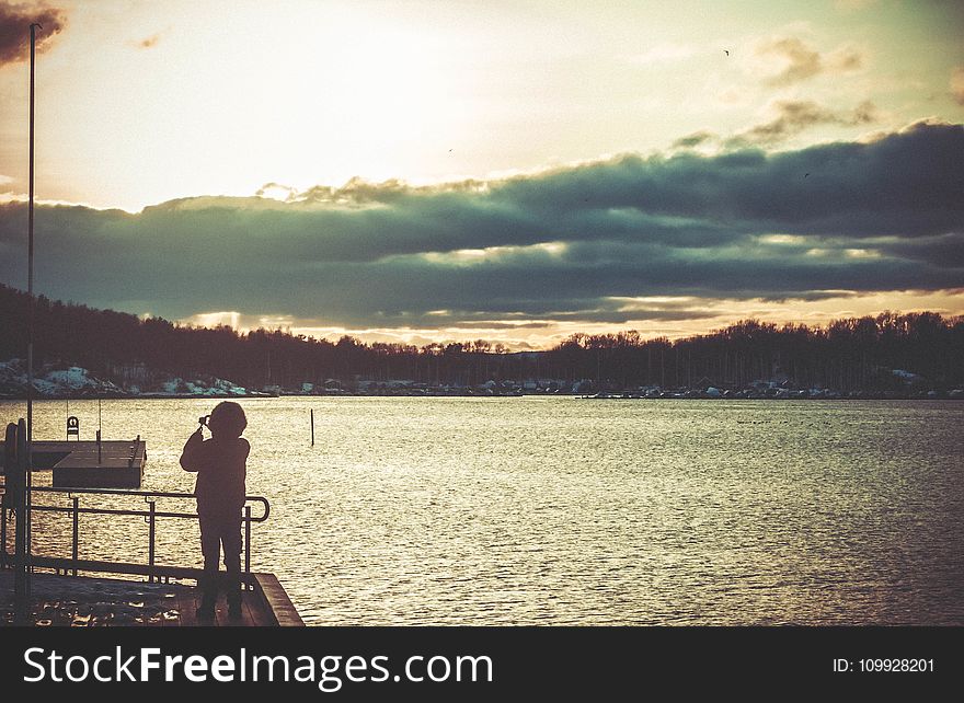 Silhouette of Person Standing on Dock