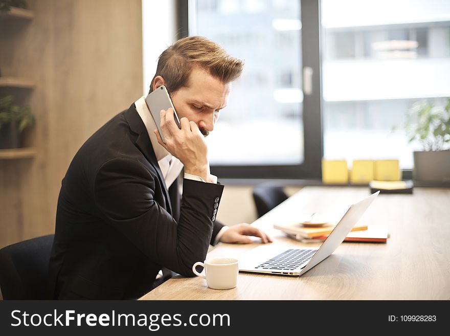 Man Having a Phone Call In-front of a Laptop
