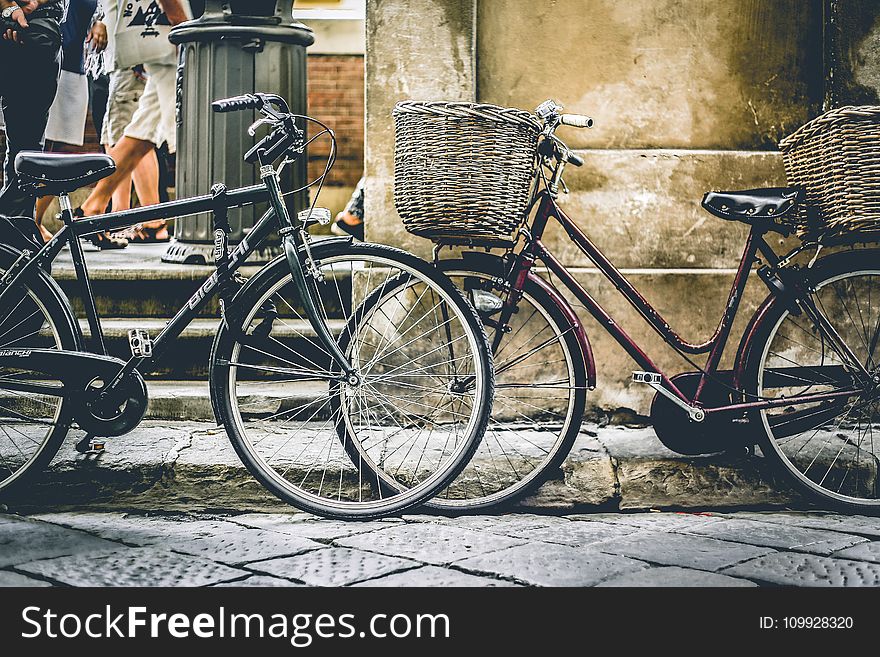 Two Black Bicycles Parting Near Wall