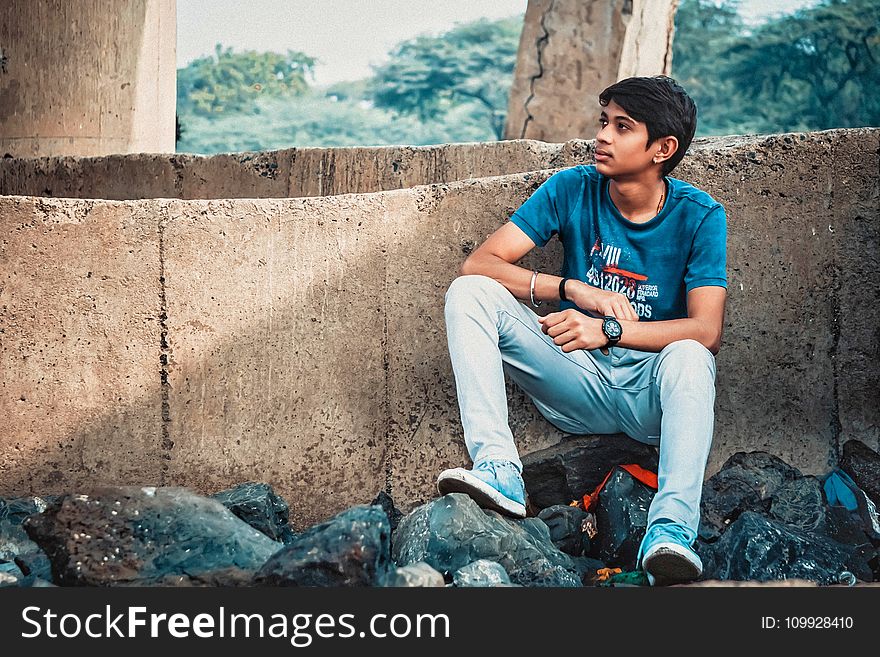 Man Sitting on Stone Leaning on Concrete Wall
