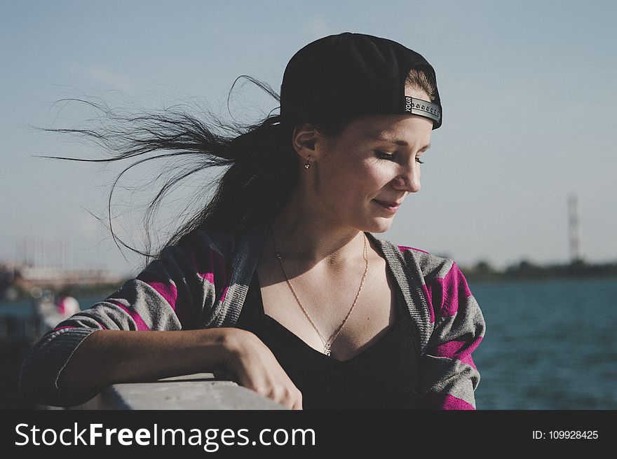 Selective Focus Photography of Female Wearing Black Snapback Near Ocean