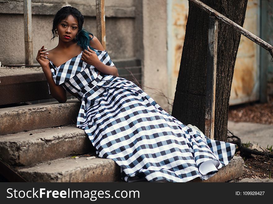Woman Wearing Black and White Checkered Spaghetti-strap Cold-shoulder Dress Sitting on the Stair
