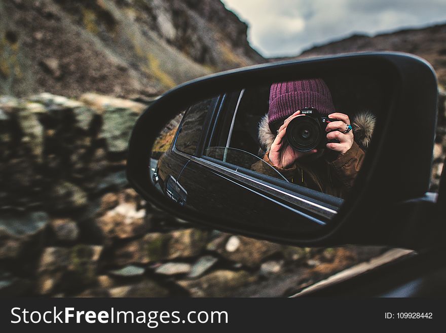 Person Holding Dslr Camera Reflected on Black Framed Wing Mirror