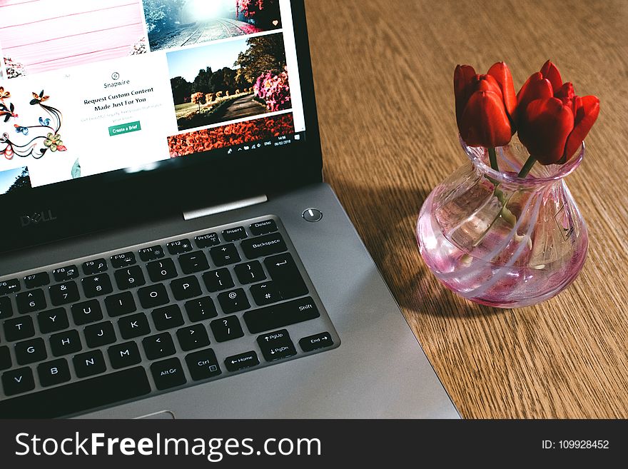 Black Dell Laptop Beside The Pink Glass Vase