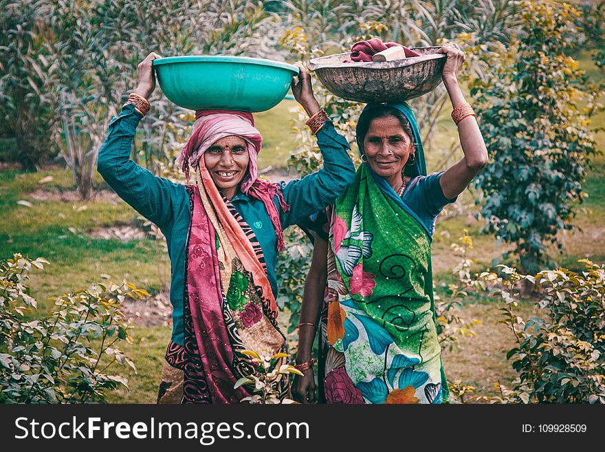 Two Women Wearing Traditional Dress Carrying Basins