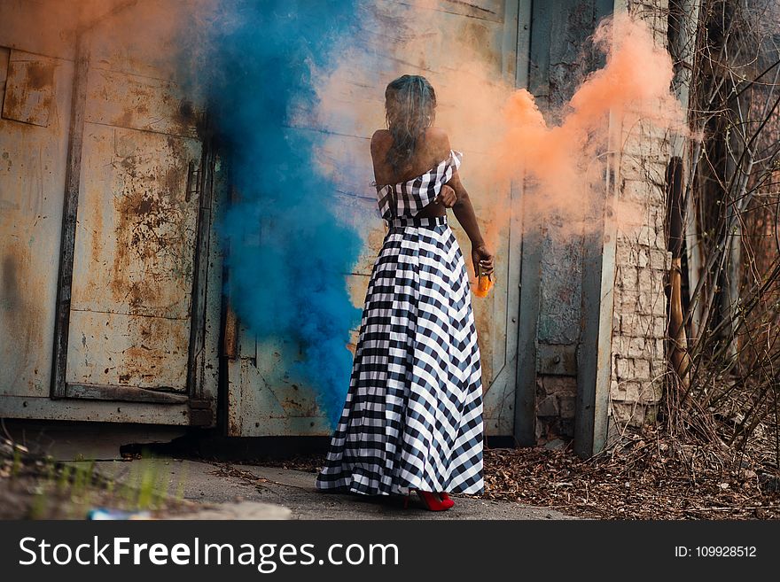 Woman Standing on Orange and Blue Smoke