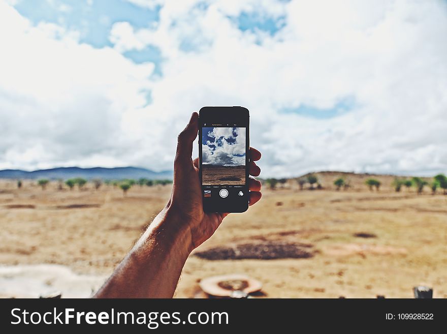 Person Holding Smartphone Showing Cloudy Sky