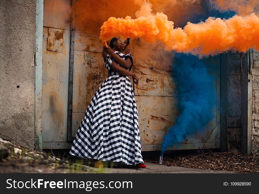 Woman in White and Black Dress Holding Orange Smoke