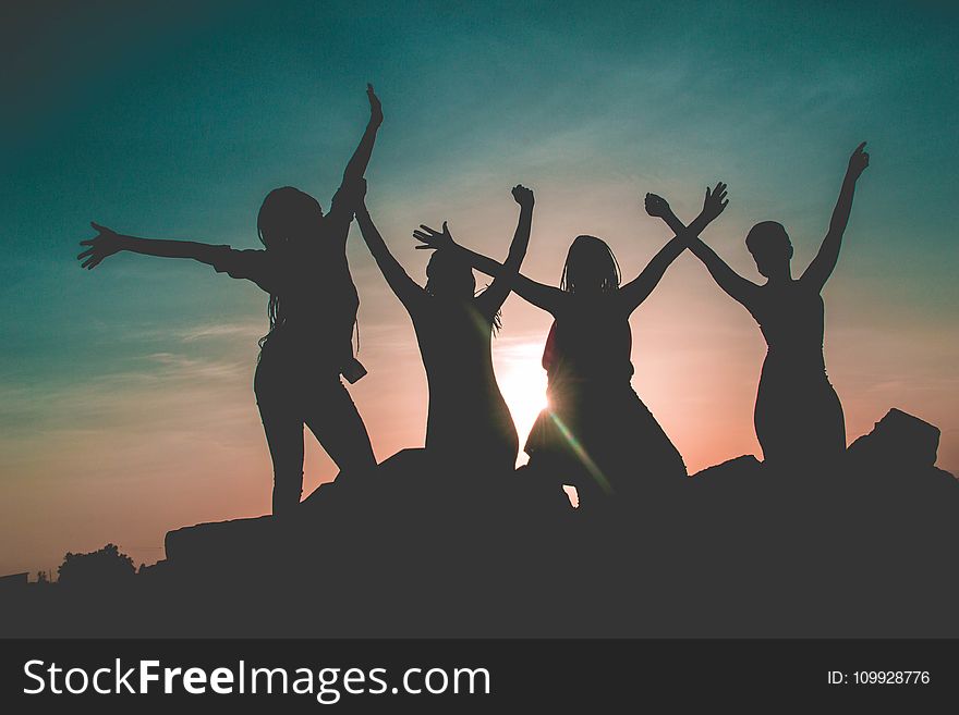 Silhouette of Four People Against Sun Background