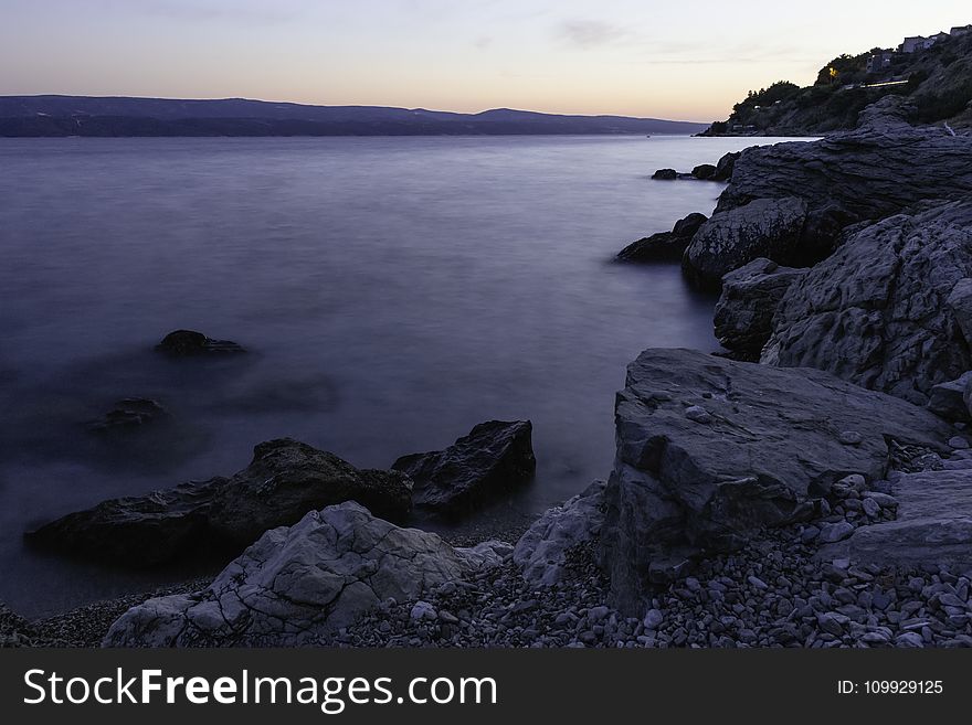 Photo of Calm Body of Water Beside Rock Formations