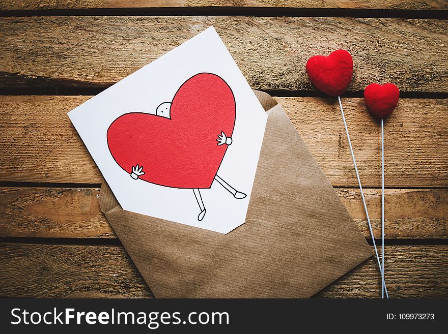 White, Black, and Red Person Carrying Heart Illustration in Brown Envelope