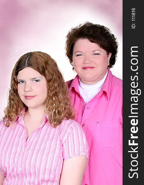 Portrait of mother and teen daughter over pink, wearing pink. Shot with the Canon 20D. Portrait of mother and teen daughter over pink, wearing pink. Shot with the Canon 20D.