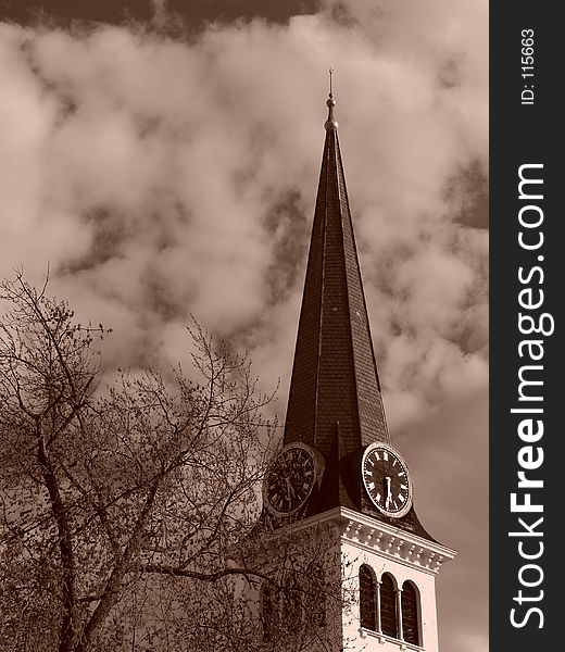 Sepia toned image showing steeple of old new england church in the spring time with tree in bloom and thick clouds