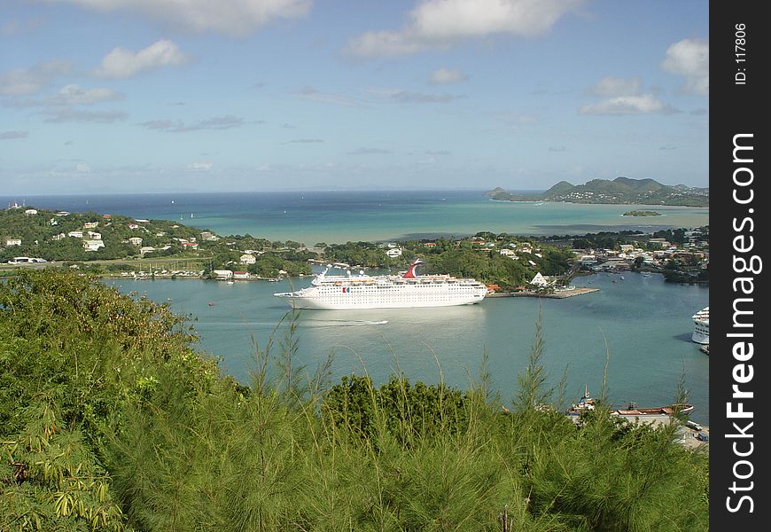 This cruise ship sits moored in a bay on a tropical island.