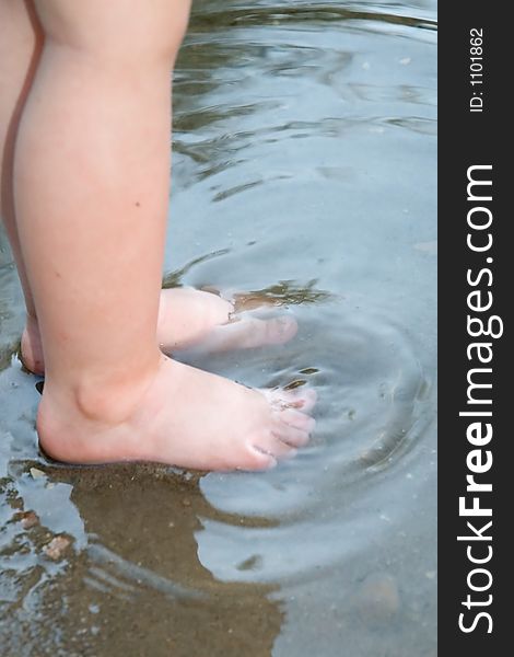 A child's toes getting wet in a lake