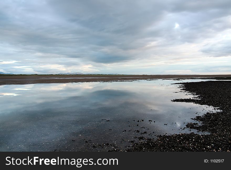 Sky reflected in tidal pool,mountain range in the distance. Sky reflected in tidal pool,mountain range in the distance