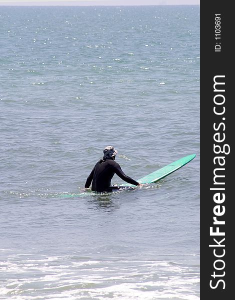 Surfer setting on green board waiting for next big wave. Surfer setting on green board waiting for next big wave.