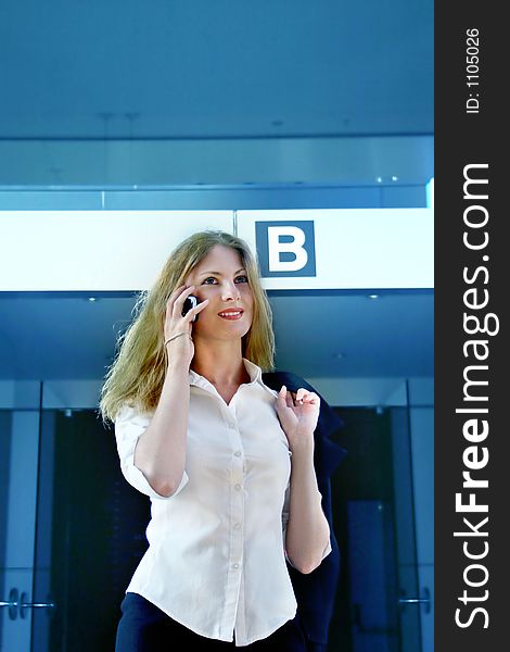 Dinamic young business woman exits a corporate bulidind during a phone conversation. Dinamic young business woman exits a corporate bulidind during a phone conversation