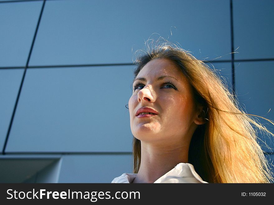 Confident young business woman basking in dusk light in front of her office building. Confident young business woman basking in dusk light in front of her office building