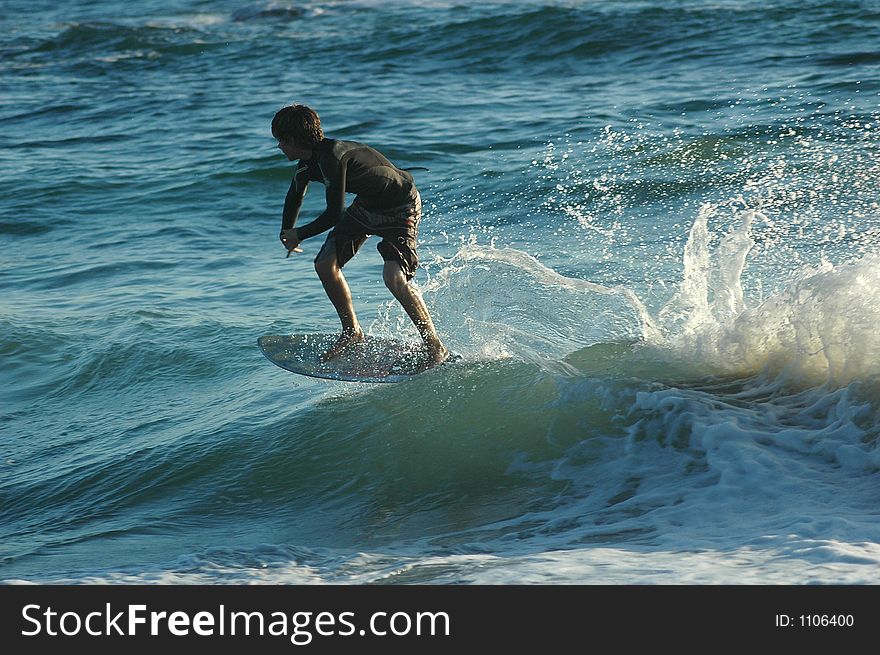 A boy on a skim board catching the wave. A boy on a skim board catching the wave