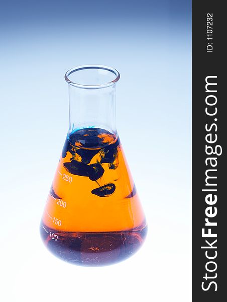 A laboratory glas filles with orange liquid and black clouds in it