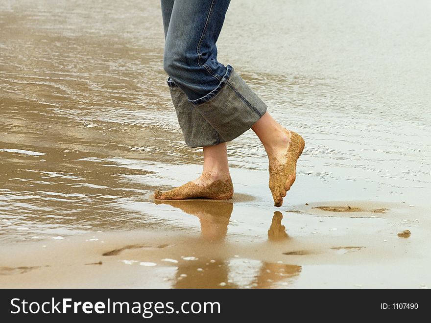 Legs of a girl is walking on the beach