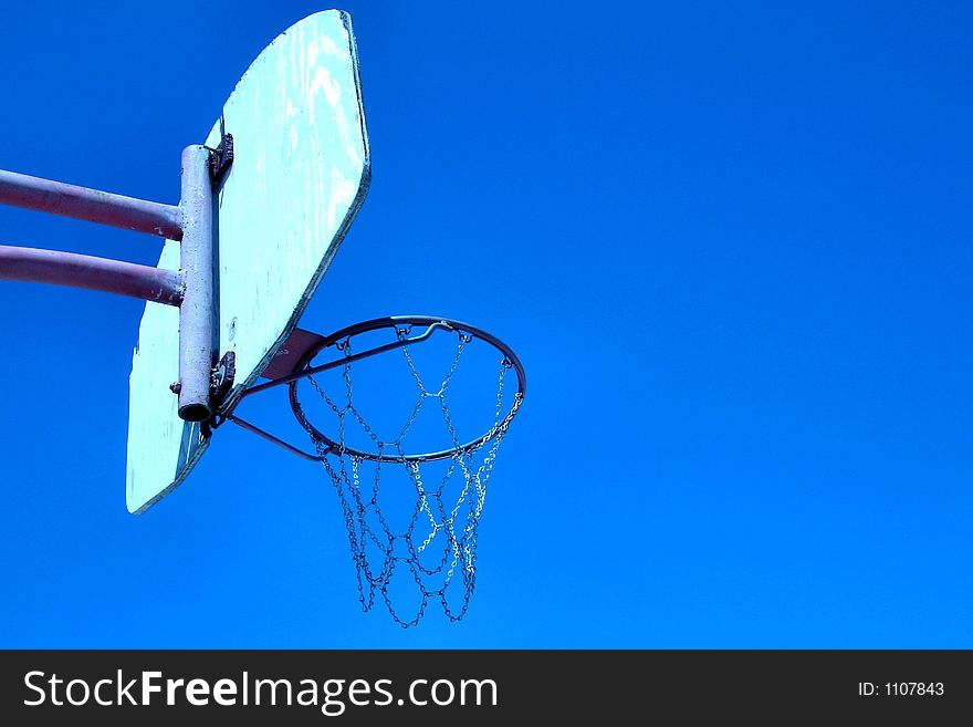 Old basketball hoop against a blue sky.