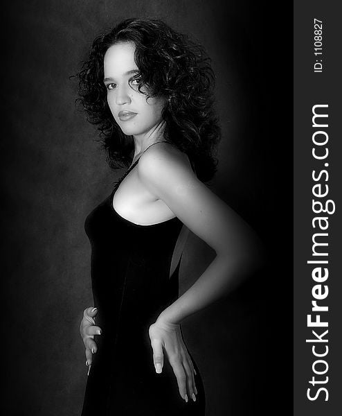 Portrait of the harmonous girl in a black dress on a dark background. b/w. Portrait of the harmonous girl in a black dress on a dark background. b/w