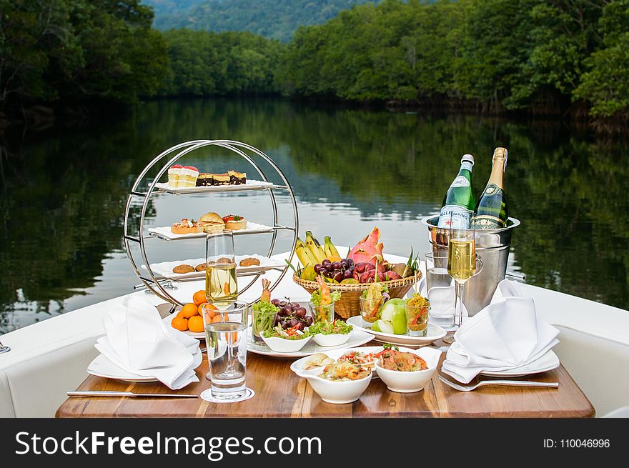Food Photography of Food and Wine Bottles on Table Inside Boat